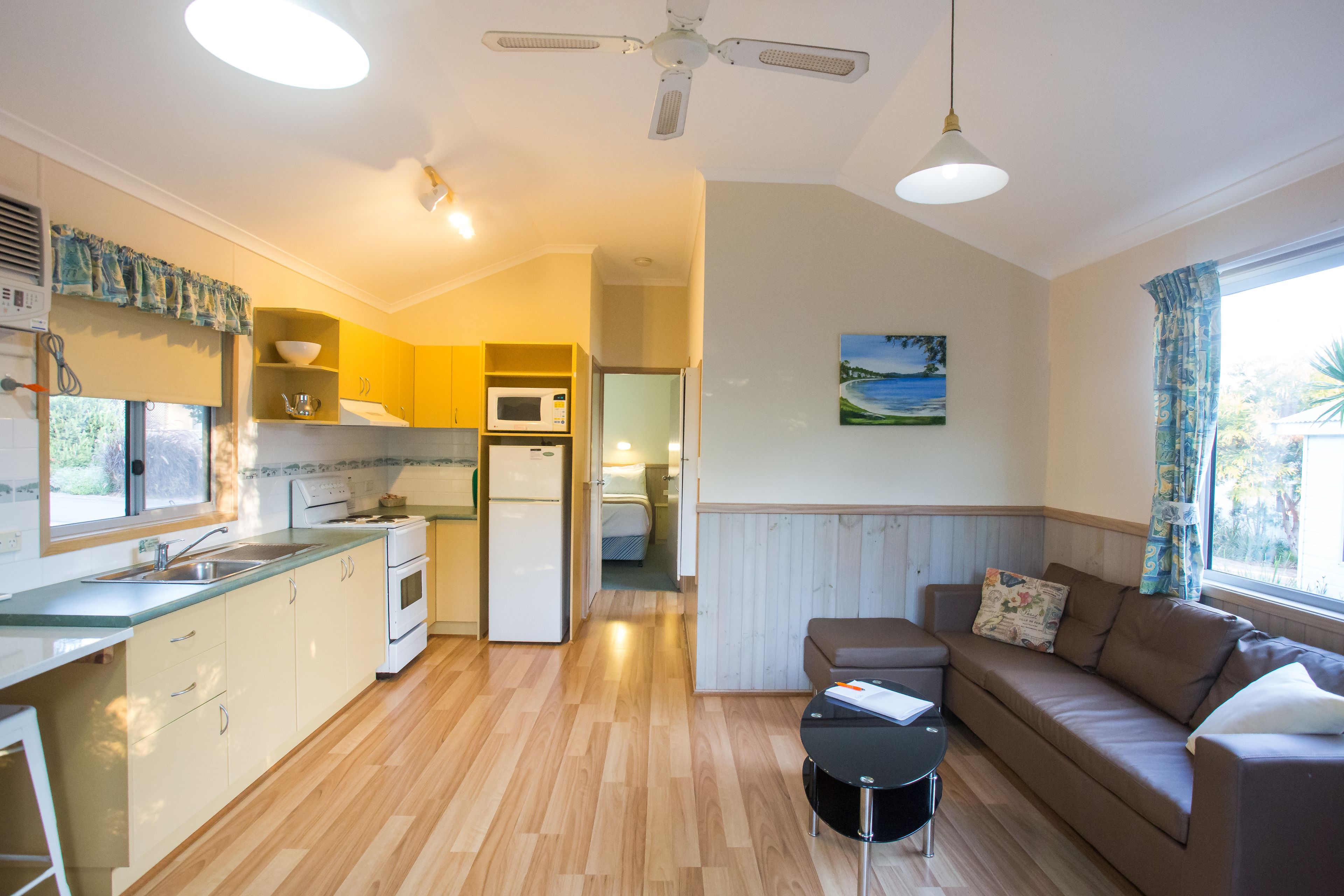 Un espacio habitable compacto con kitchenette, comedor y zona de estar con sofá y una mesita.