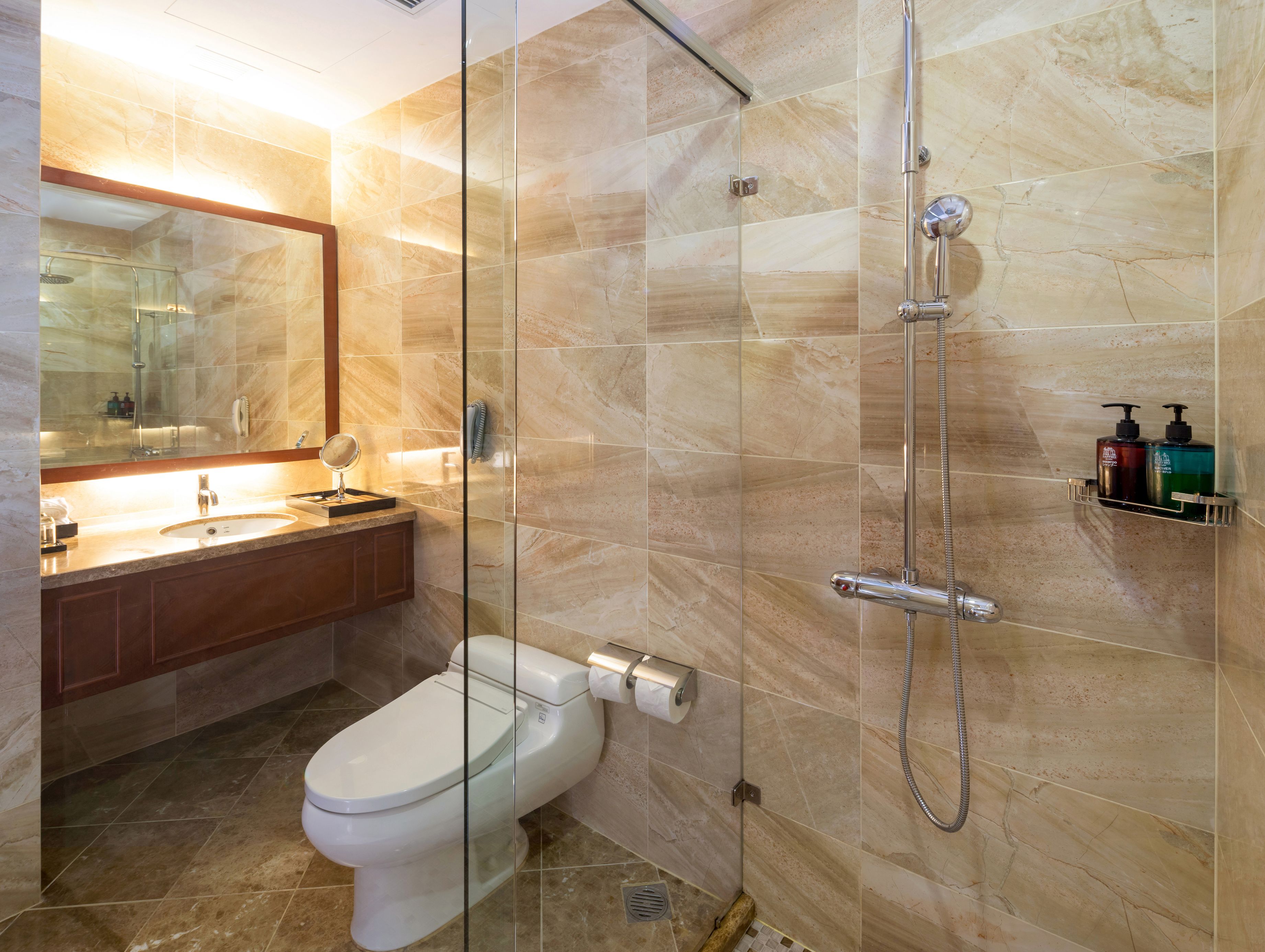 A modern bathroom with a glass-enclosed shower, a toilet, a sink with a mirror, and a shelf with toiletries.