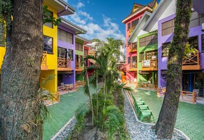 A courtyard with colorful buildings, outdoor seating, and palm trees. - The Club Ten Beach Resort Boracay (Malay)