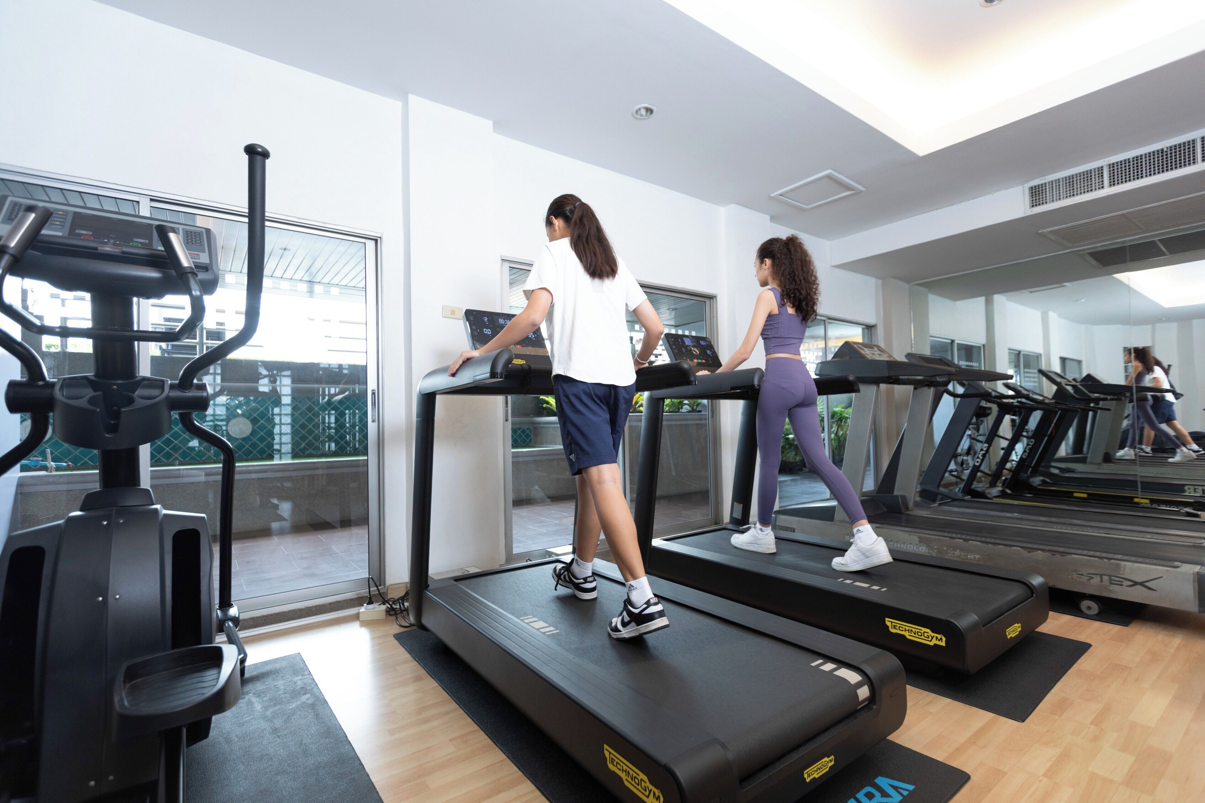A gym with treadmills, a stationary bike, and a large window.