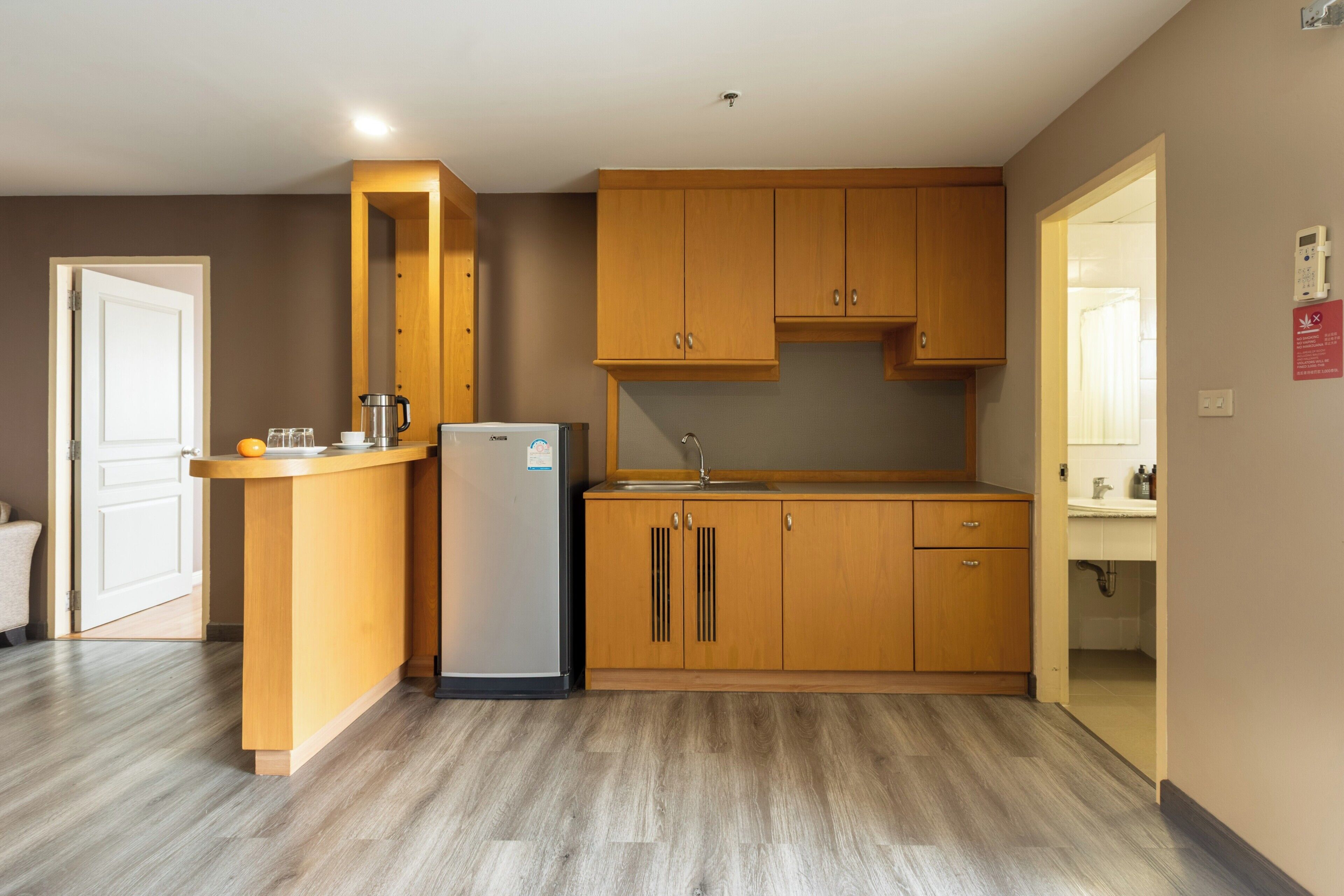 Eine kleine Küche mit Holzschränken, einer eingebauten Spüle und einem Kühlschrank.