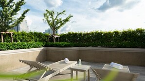 Una terraza con sillones de sol, una mesita y una toalla.