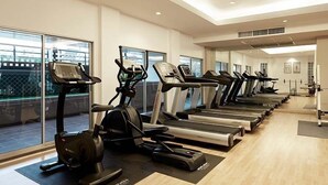 Un gimnasio con numerosas cintas de correr y bicicletas estáticas, ventanas amplias y un diseño moderno y limpio.