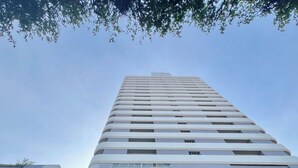 Un edificio moderno de gran altura con fachada de vidrio y una entrada central con toldo de cristal.