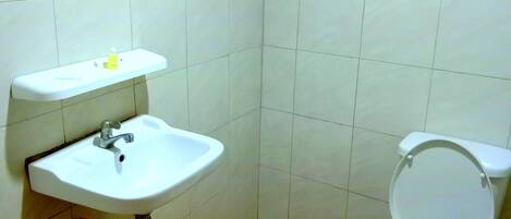 Un baño con lavamanos blanco, espejo y retrete.