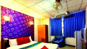 Ein Hotelzimmer mit Bett, Schreibtisch, Stuhl, Fernseher und Klimaanlage.