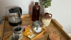 A wooden tray with a coffee maker, a glass jar, a ceramic jug, a plant, and a packet of biscuits. - The George Hotel (Penrith)