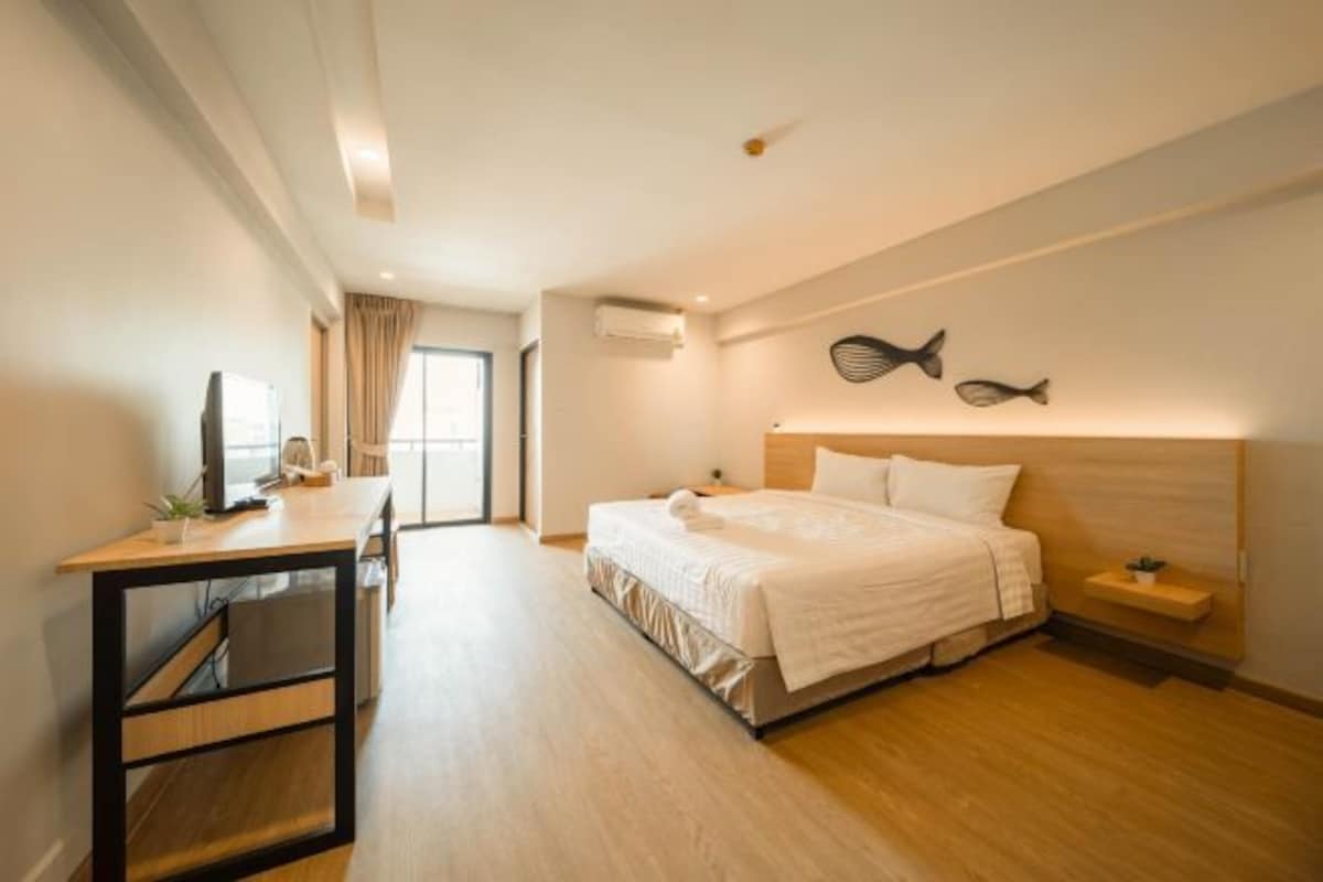 A hotel room with a bed, a desk, a television, and a view of the outdoors.