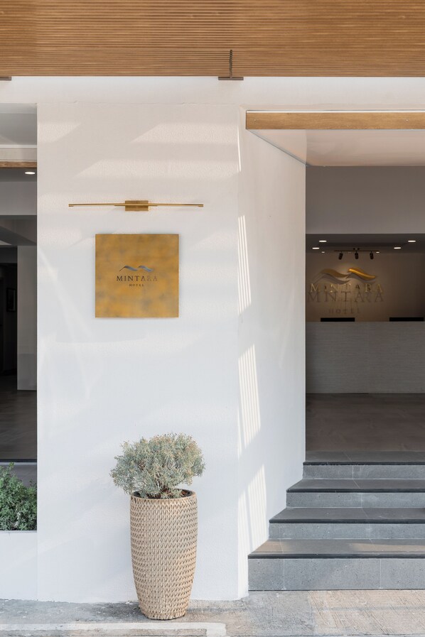A reception area with a reception desk, a potted plant, and a staircase leading to an upper level.