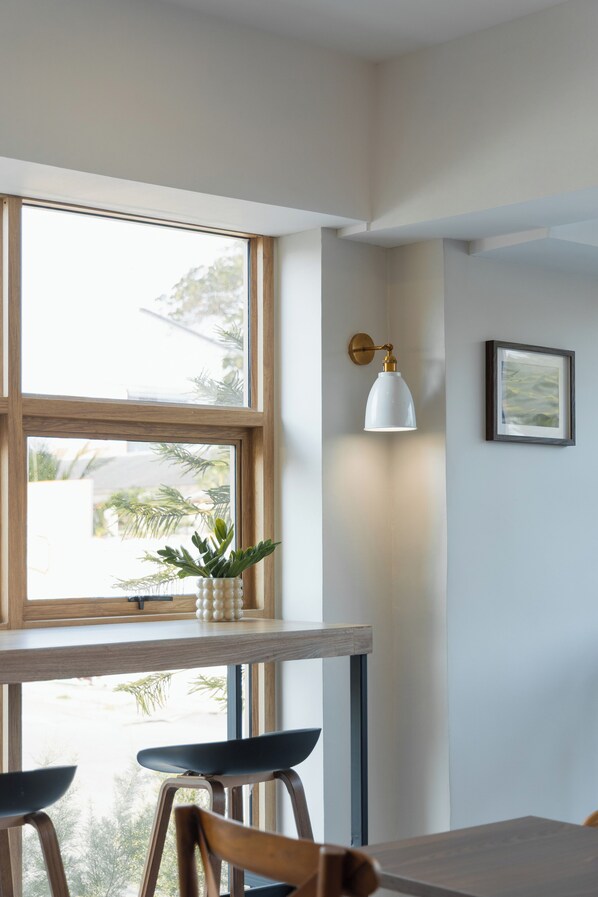 A modern kitchen with a wooden countertop, a white pendant light, and a framed picture on the wall.
