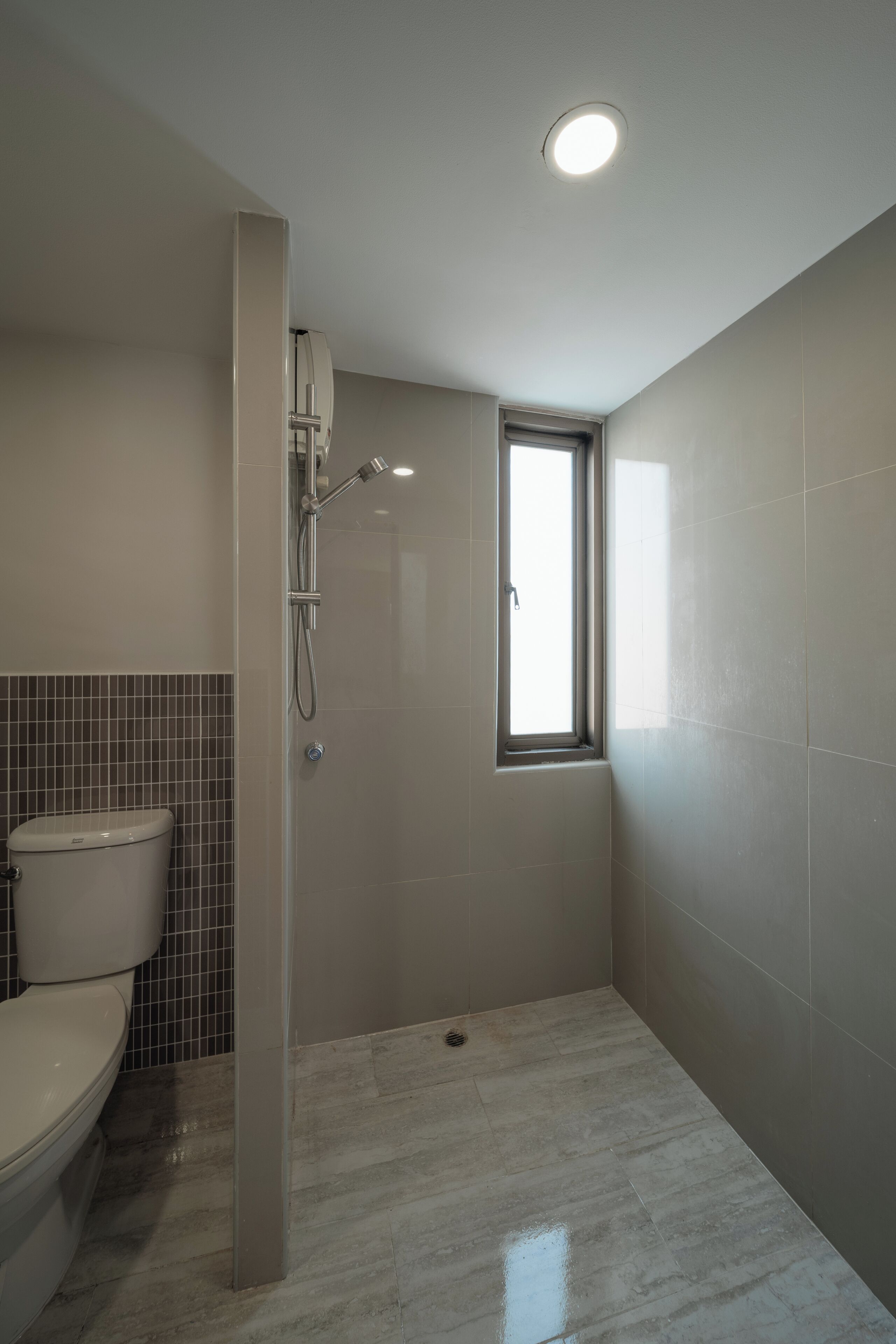 A bathroom with a toilet, a shower, and a window.