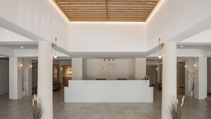 A modern hotel reception area with a central white reception desk, large columns, and minimalistic decor. - Mintara Hotel (Bangkok)