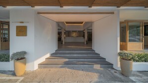 A modern building entrance with a staircase leading to a reception area. - Mintara Hotel (Bangkok)