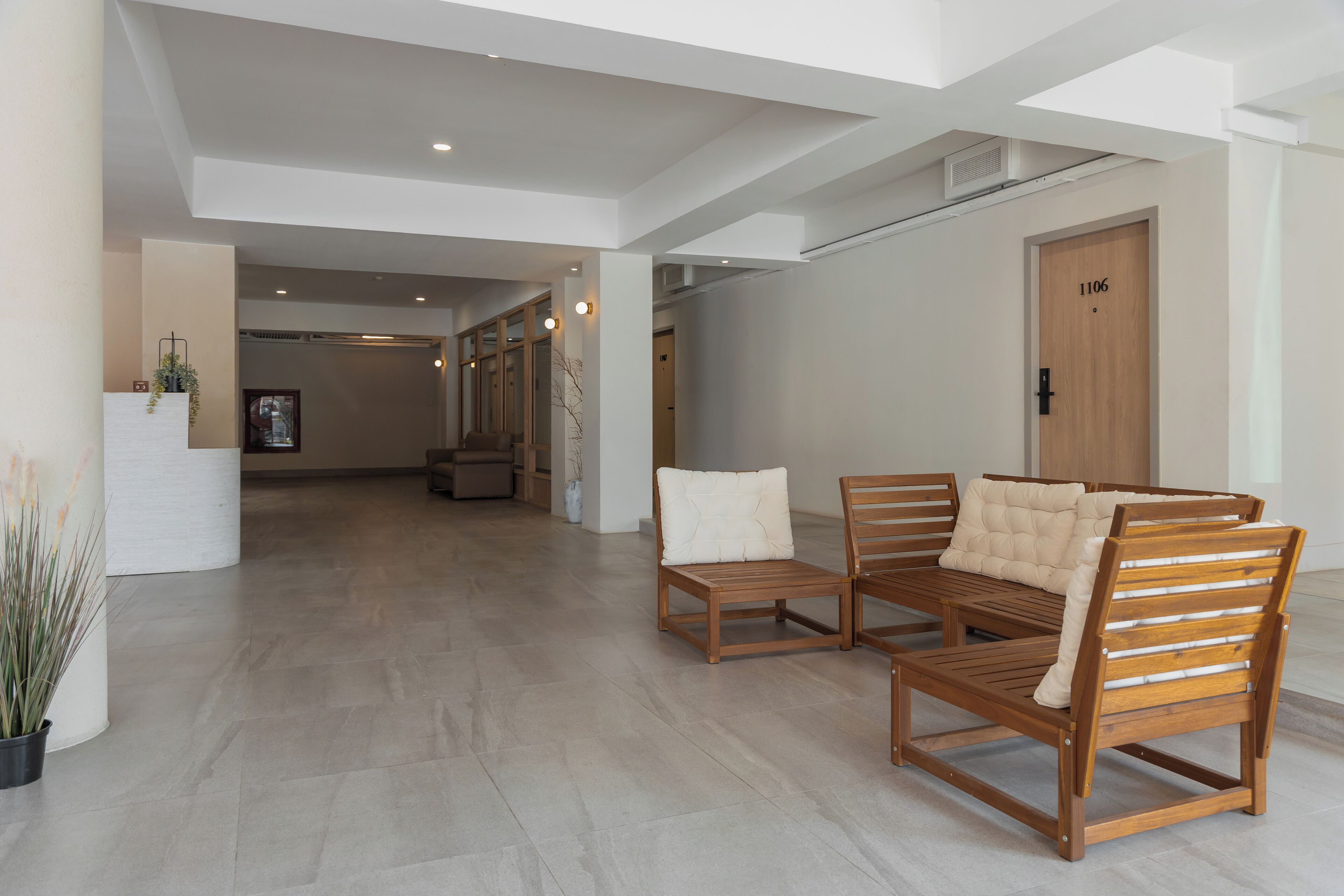 A spacious lobby with wooden furniture, a reception desk, and a door marked 1106.