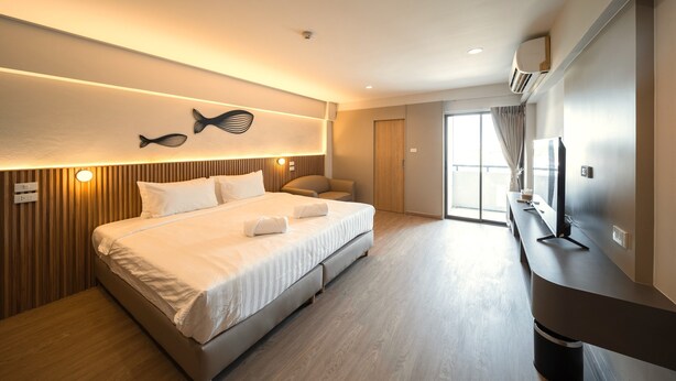 A modern hotel room with a large bed, a flat-screen TV, and a view of the outdoors. - Mintara Hotel (Bangkok)
