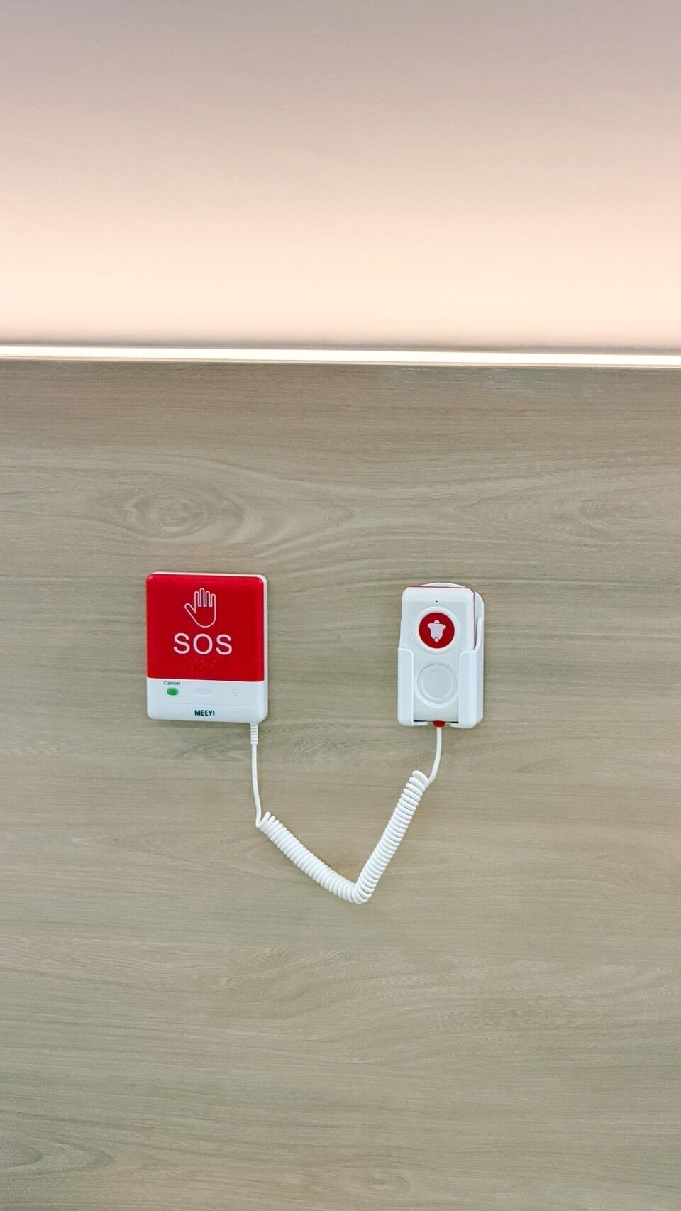 Un botón de llamada de emergencia SOS montado en la pared, con un auricular conectado.