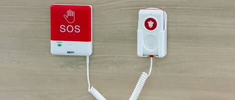 Un botón de llamada de emergencia SOS montado en la pared, con un auricular conectado.