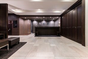 A modern lobby with a reception desk, seating area, and a fireplace.