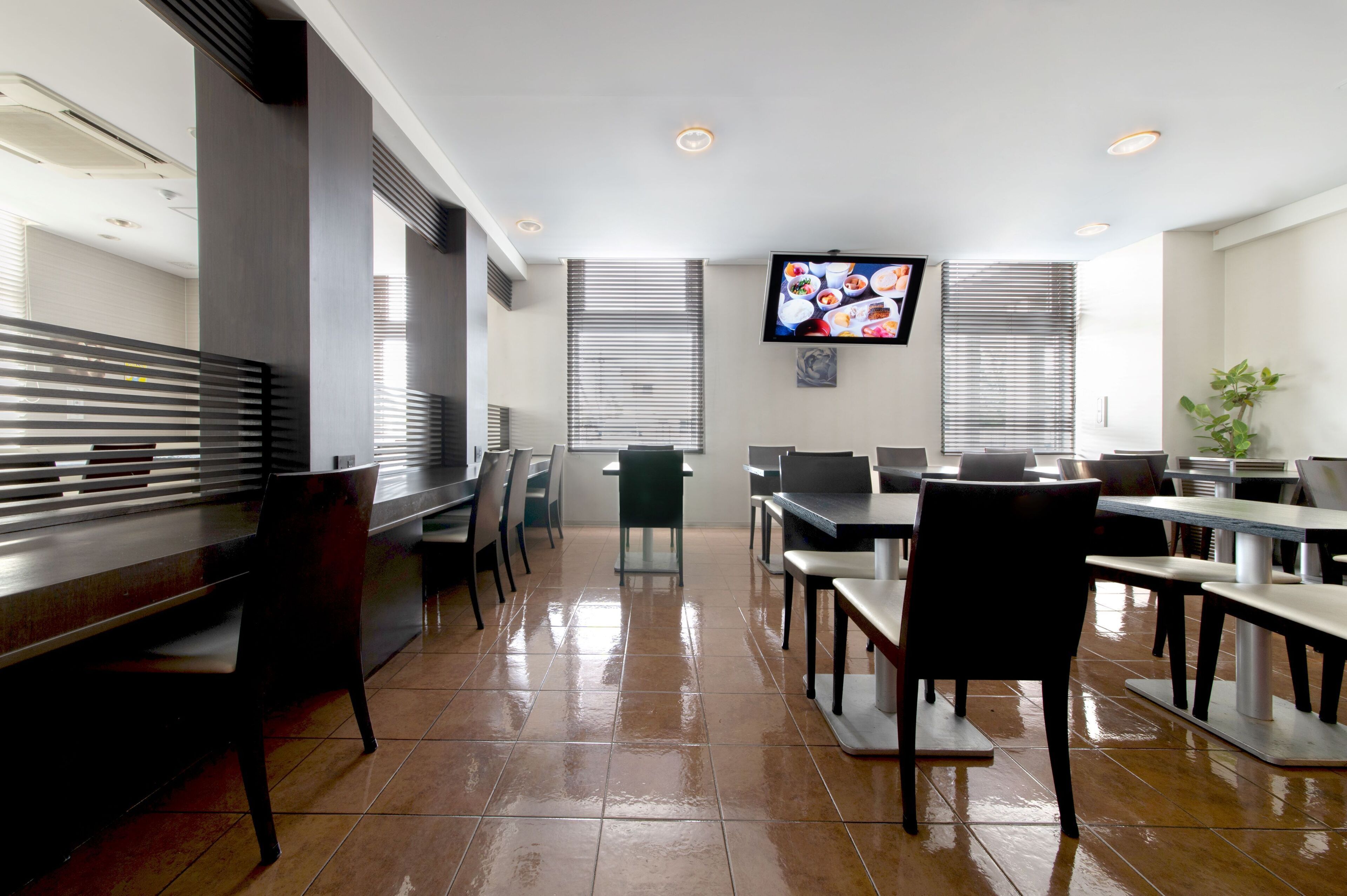 Un restaurant doté d’un long comptoir, de plusieurs tables et de chaises.