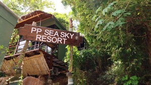 Placa de madeira do PP Sea Sky Resort em meio a vegetação exuberante.