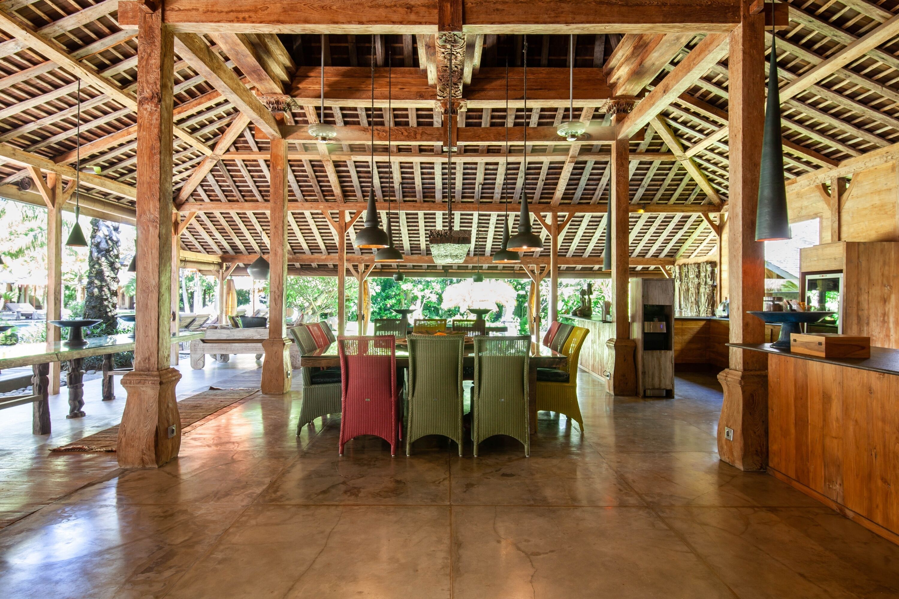 A spacious indoor area with a high wooden ceiling and a central table surrounded by chairs.