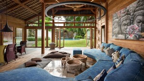 Una habitación amplia con un sofá azul grande, muebles de madera y un ventilador de techo.