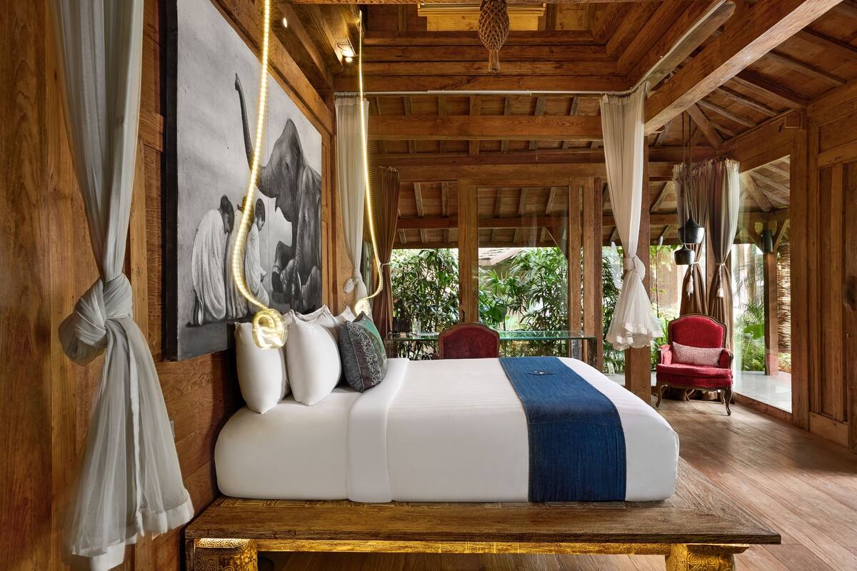 Una habitación de madera con una cama, una silla roja y un cuadro grande en la pared.