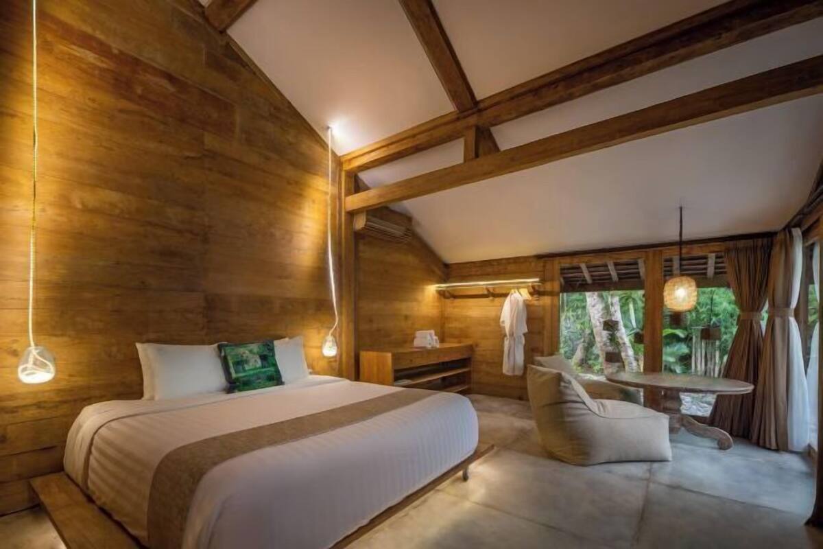 Una habitación de madera con una cama, una mesa y un banco.