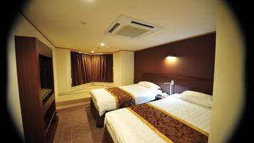 A hotel room with two beds, a wardrobe, a desk, and a window with curtains.