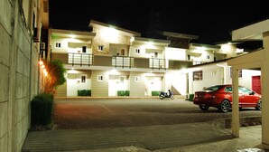 A multi-story building with a paved entrance and a red car parked in front. - Rumi Apartelle Hotel (Angeles City)