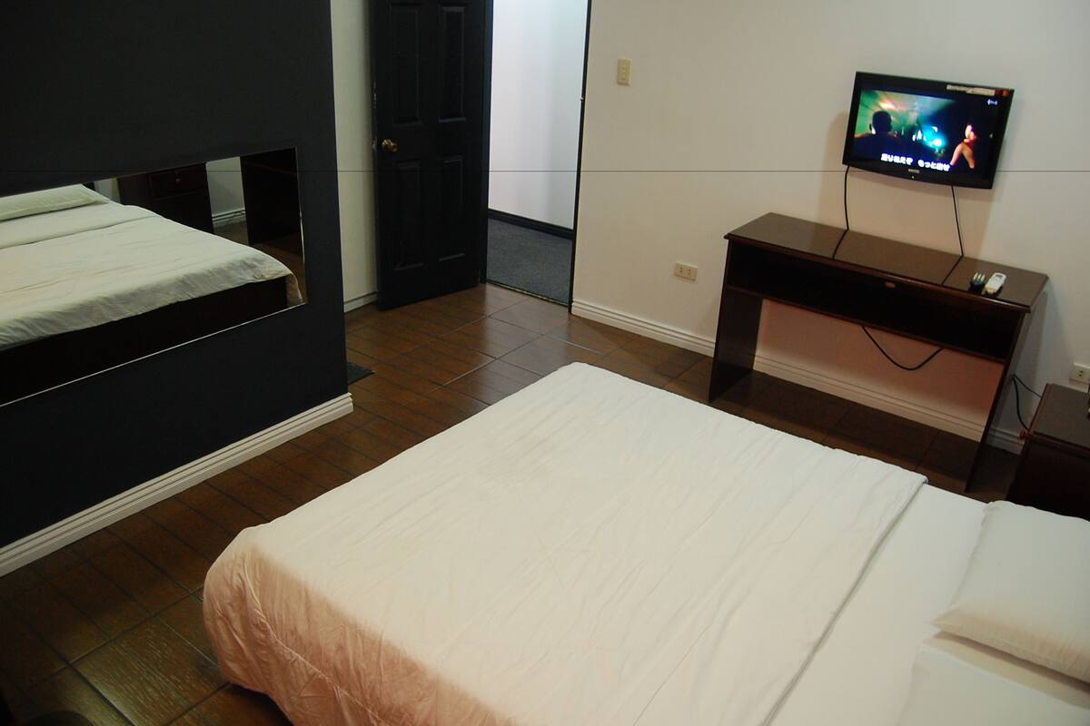 Une chambre d’hôtel avec deux lits, une télévision et un bureau.