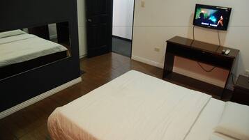 Une chambre d’hôtel avec deux lits, une télévision et un bureau.