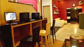 A room with two computer monitors, a white sofa, a wicker chair, and a small table with a lamp. - Rumi Apartelle Hotel (Angeles City)