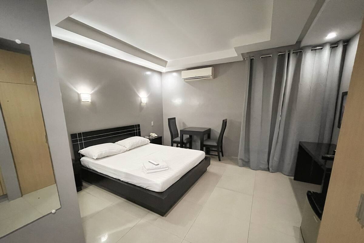 Une chambre d’hôtel moderne, dotée d’un grand lit, d’un bureau et d’une chaise.