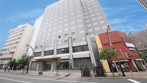 A multi-story hotel with a modern design, featuring a prominent entrance with a glass facade and a vertical strip of windows. - Vessel Inn Sapporo Nakajima Park (Sapporo)