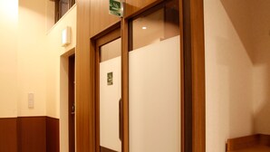 A hallway with wooden doors and a green sign indicating a smoking area. - Vessel Inn Sapporo Nakajima Park (Sapporo)