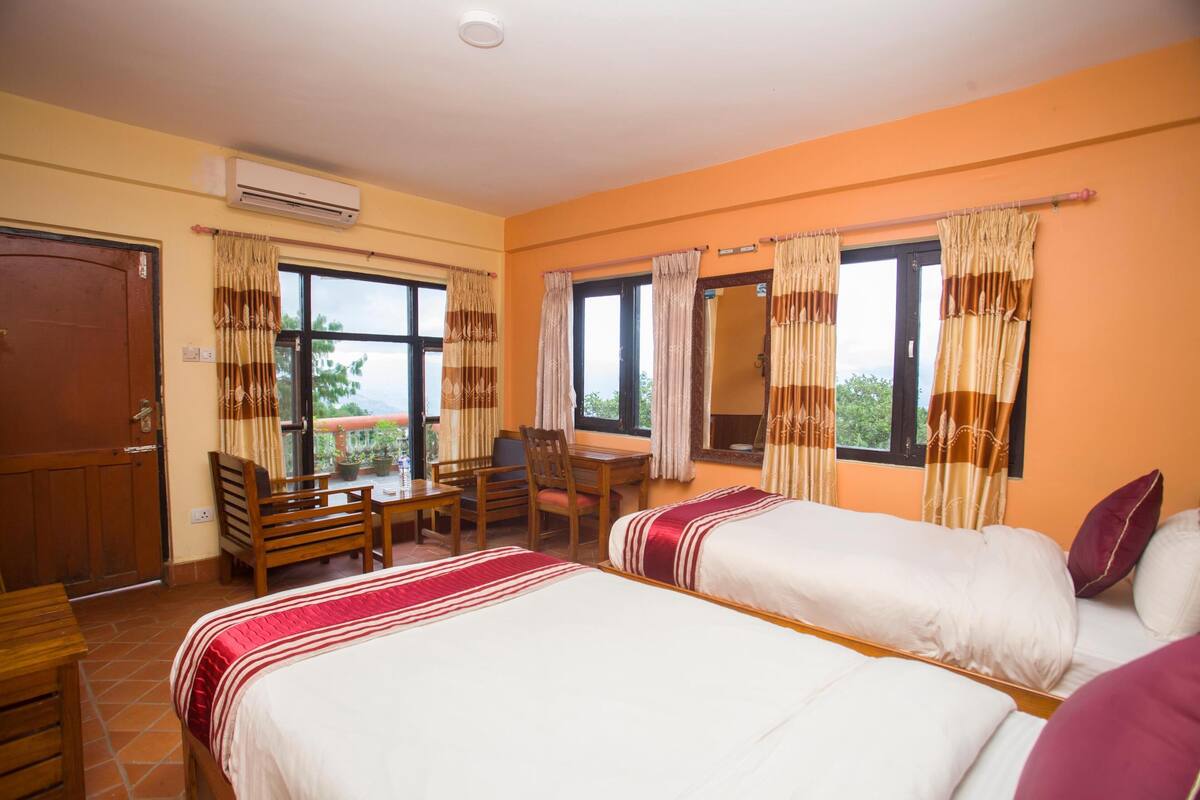 Quarto com duas camas, uma escrivaninha, cadeiras e uma janela com cortinas.