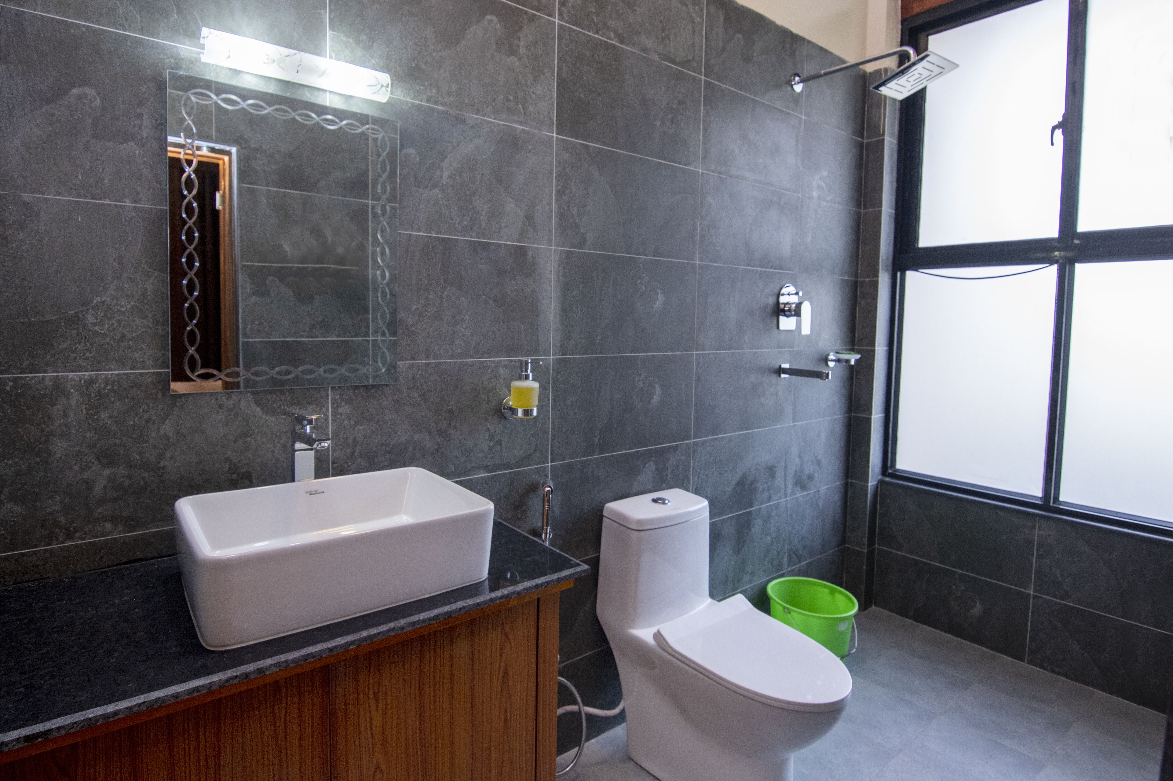 Une salle de bain moderne avec un grand miroir, un lavabo blanc, des toilettes et une douche.