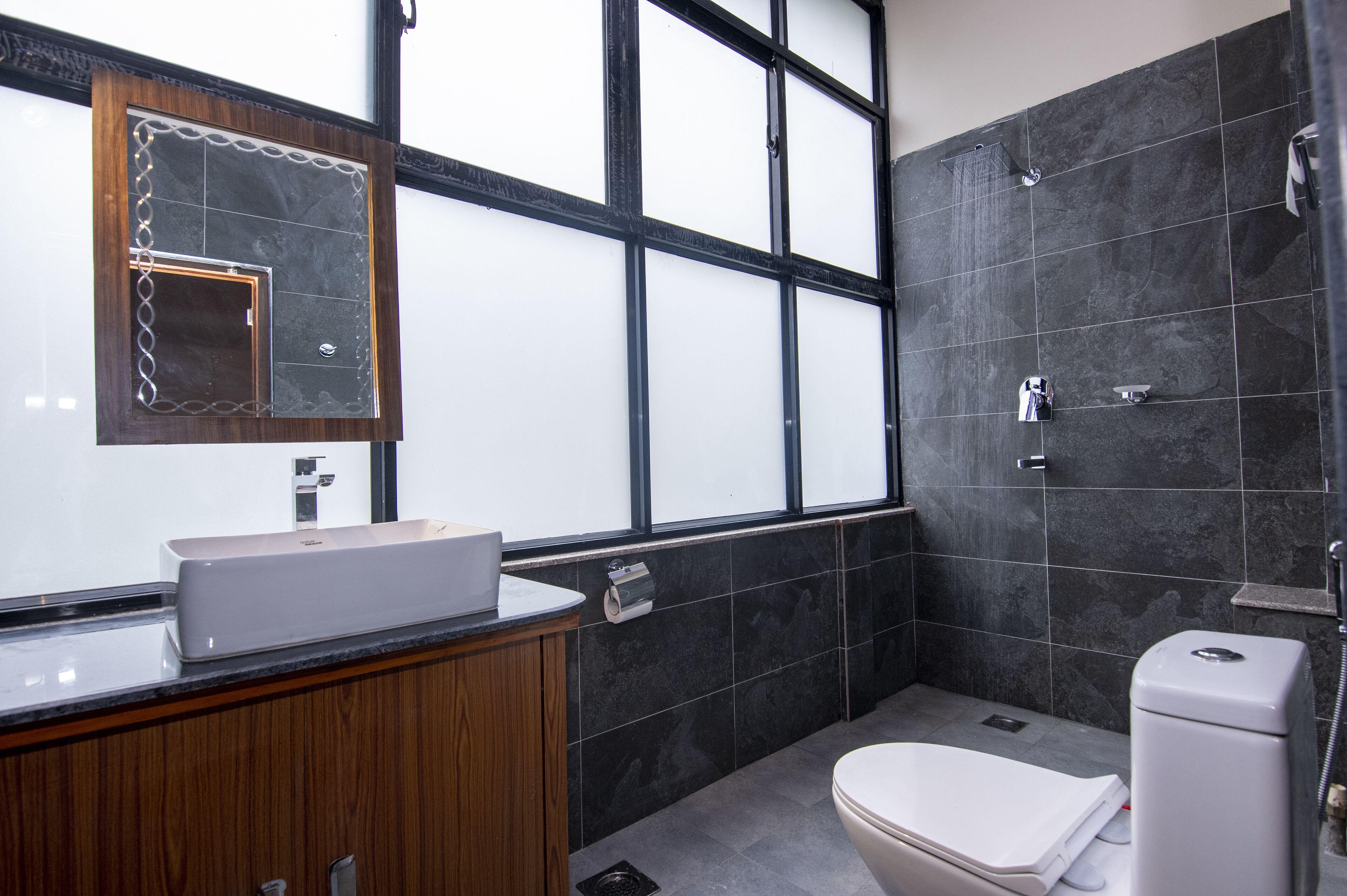 Une salle de bain moderne avec un grand miroir, un lavabo, des toilettes et un espace douche.