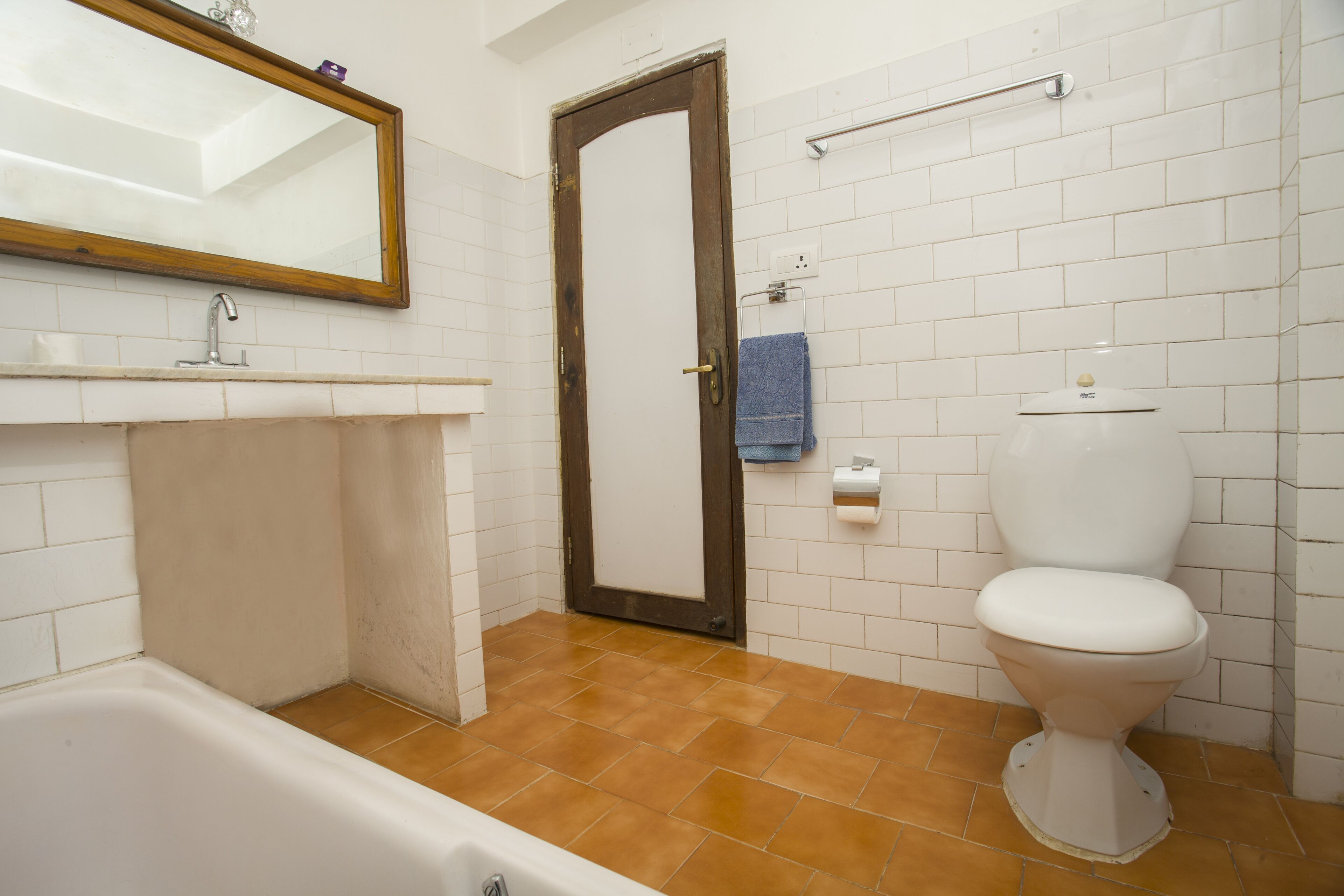 Un baño con bañera, inodoro y un espejo grande.