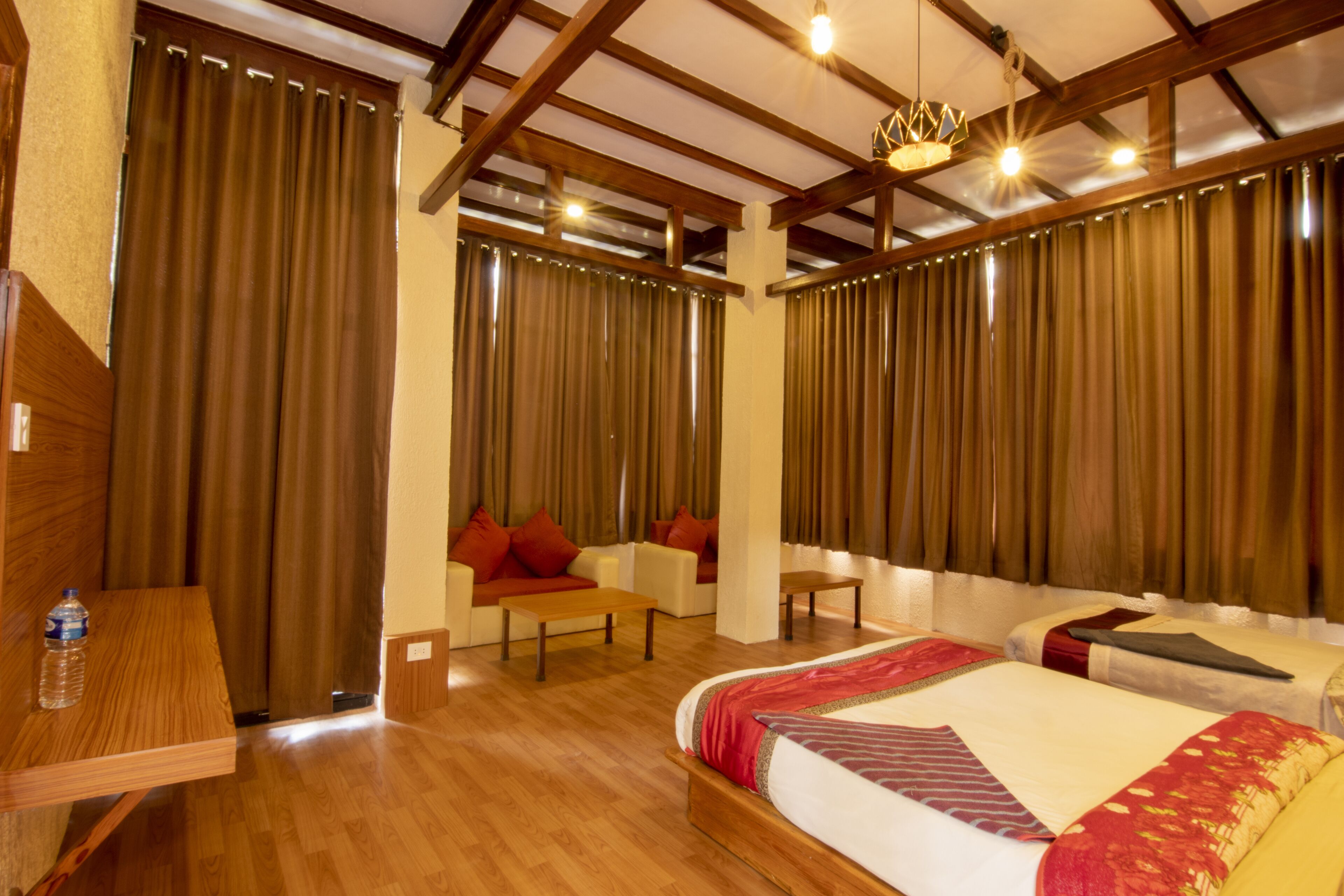 A hotel room with a large bed, two sofas, a wooden table, and a chandelier.