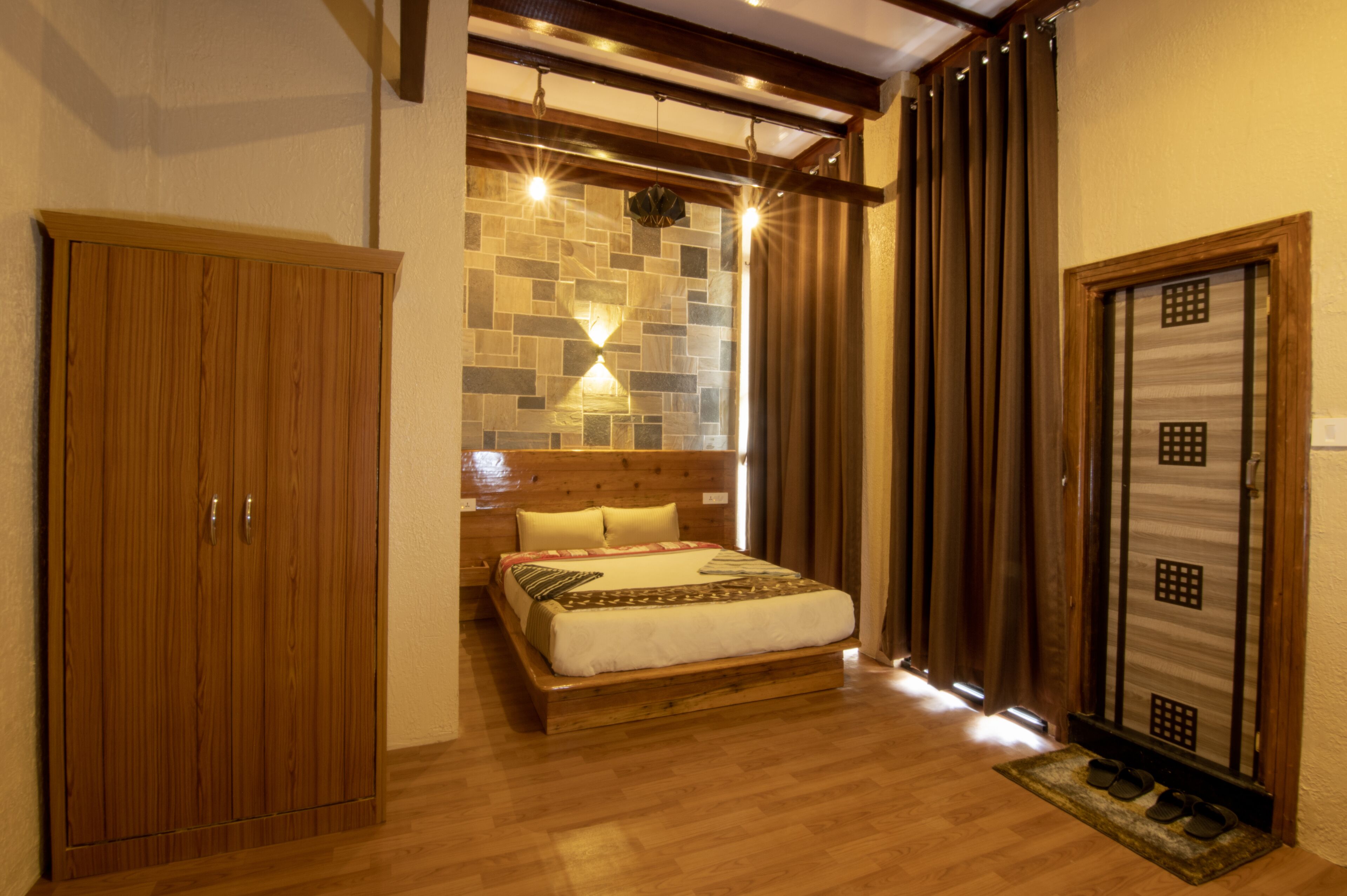 Ein Schlafzimmer mit einem hölzernen Bett, einem Kleiderschrank, einer Steinwand und einer Tür mit Rastern.