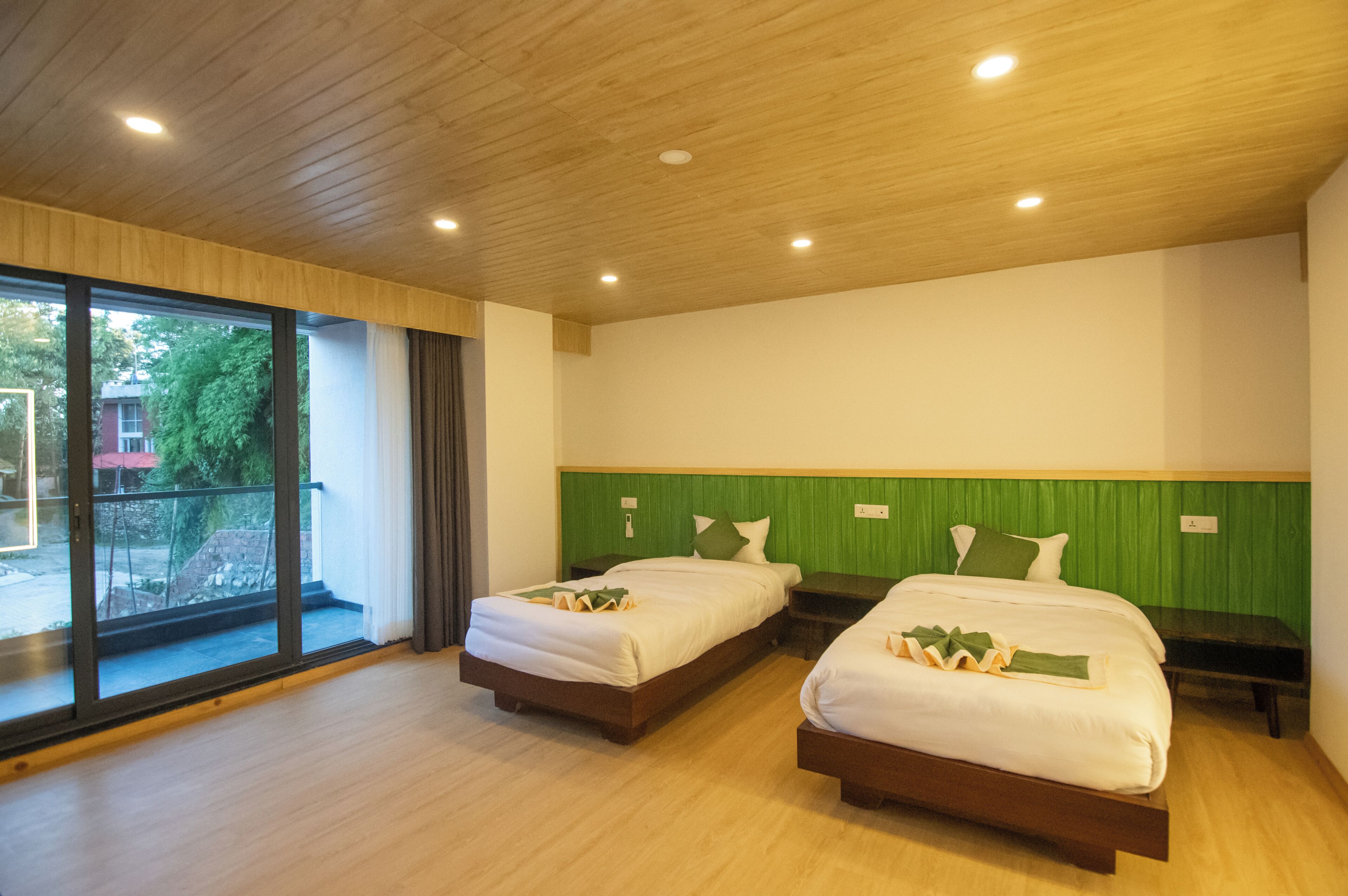 A hotel room with two beds, a balcony, and a green accent wall.