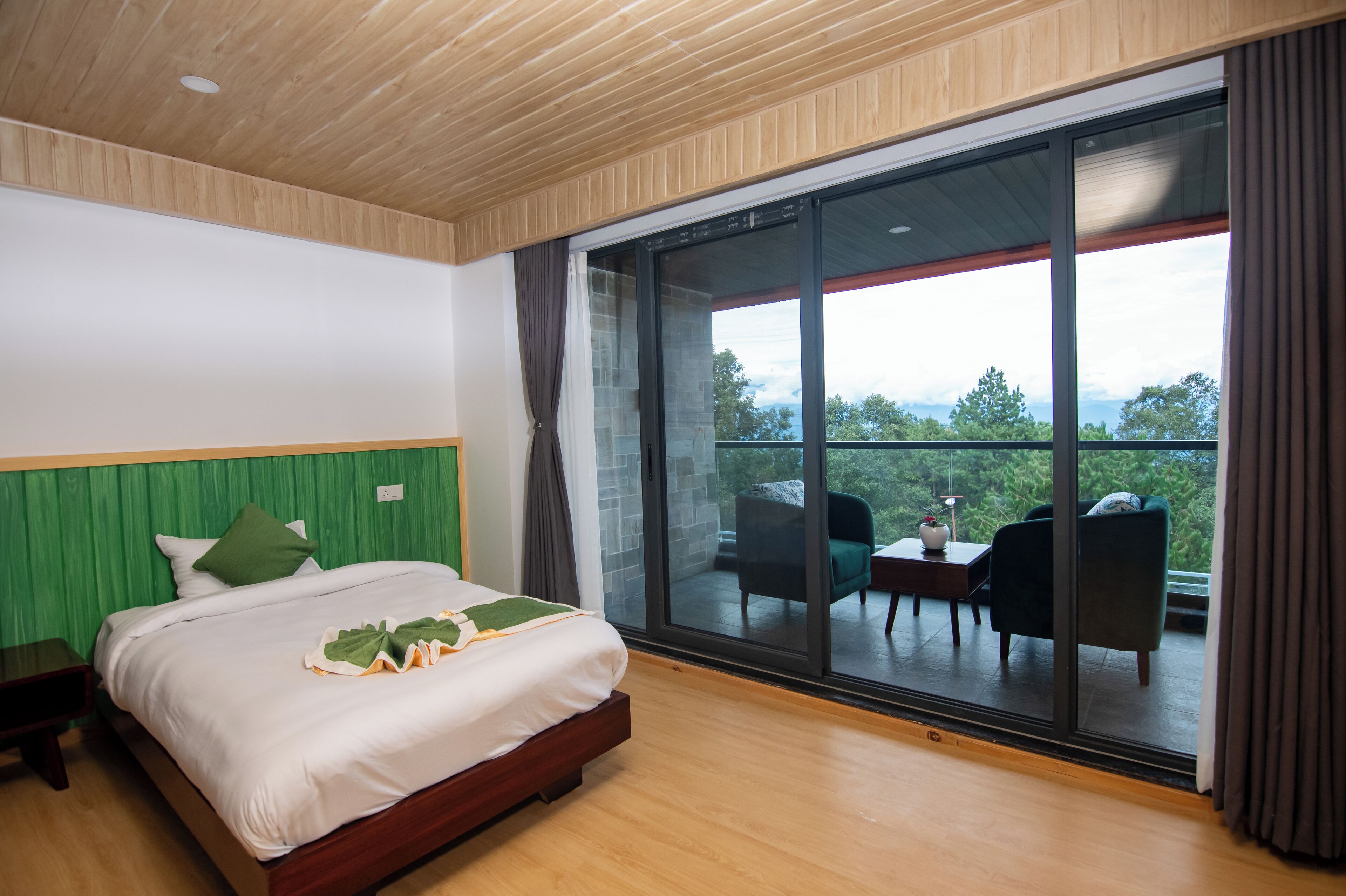 A bedroom with a large bed, a wooden ceiling, and a sliding glass door leading to an outdoor seating area.