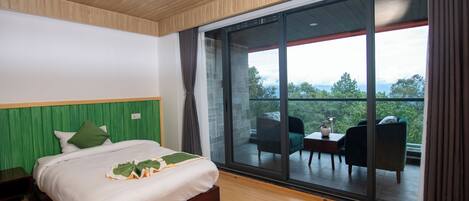 A bedroom with a large bed, a wooden ceiling, and a sliding glass door leading to an outdoor seating area.