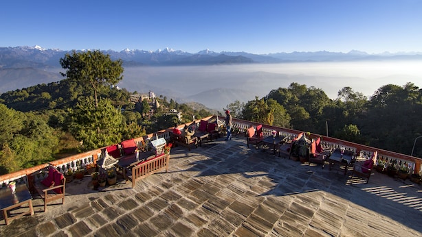 Eine Terrasse mit Steinboden, Sitzgelegenheiten im Freien und Topfpflanzen.