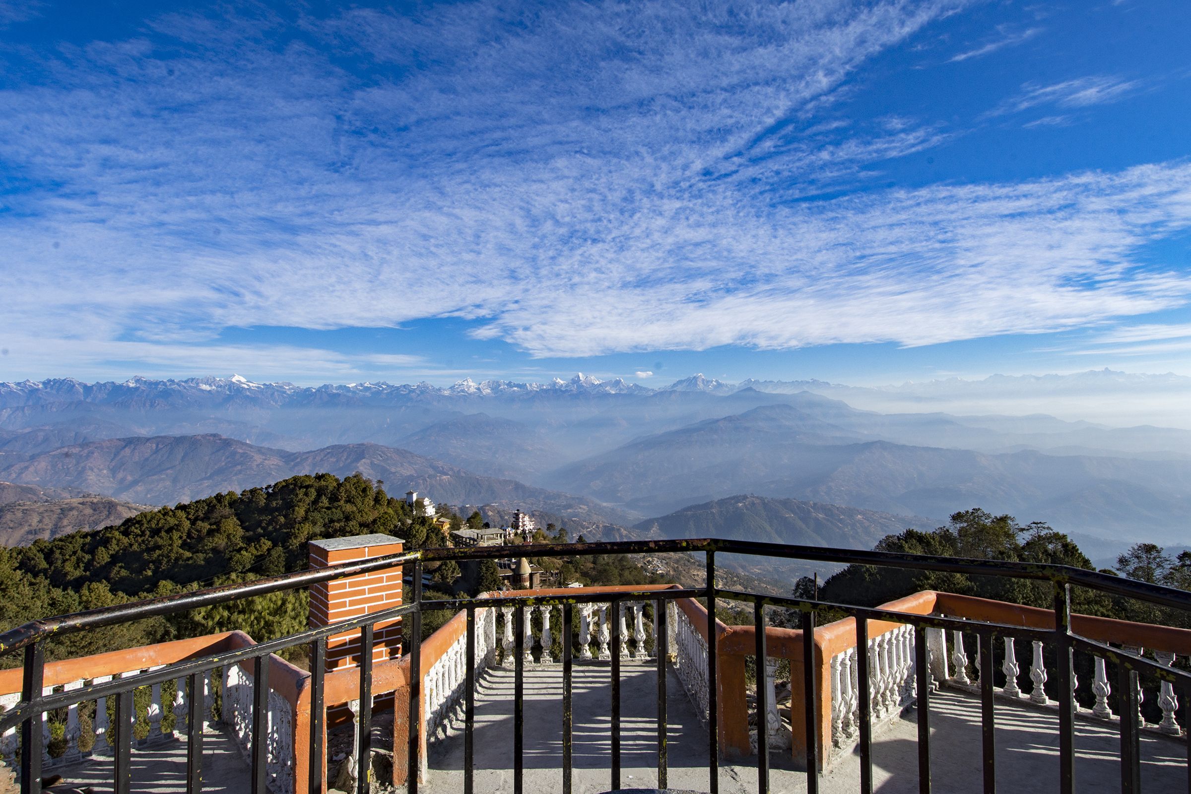 Escadaria que leva a um mirante com vista para montanhas distantes e céu claro.