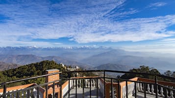 Escadaria que leva a um mirante com vista para montanhas distantes e céu claro.