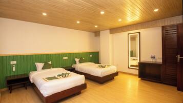 A hotel room with two beds, a green headboard, a wooden ceiling, and a mirror with a light.