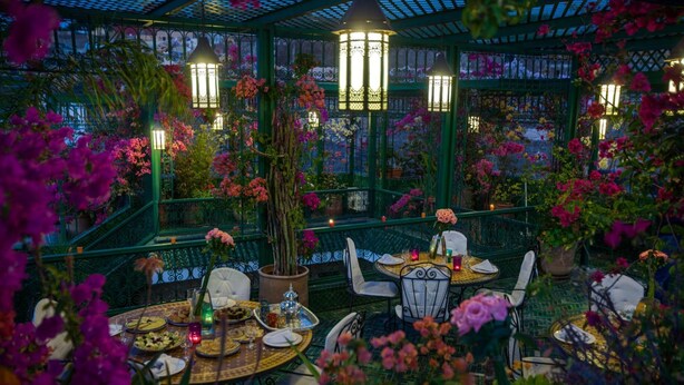 A cozy outdoor dining area with tables and chairs, surrounded by lush greenery and flowers. - Riad La Maison Verte (Fes)